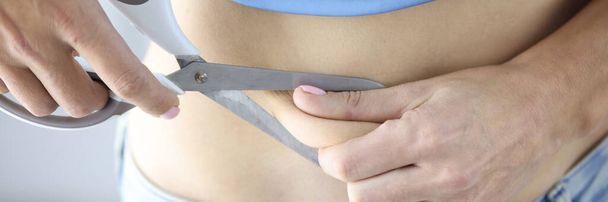 Nainen leikkaa lihavan palan saksilla. Ylipaino ja rasvaimu käsite - Valokuva, kuva