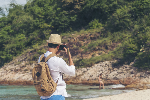 Man traveler using digital camera on summer beach blue sky take a photo. Asian Photographer man journey relax on the beach in summertime. Man backpack shooting photo asia destination holiday trip - Foto, Imagem