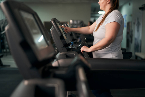Part of plus size caucasian woman preparing for running on treadmill at gym - Photo, Image