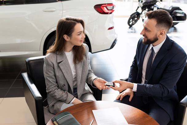 car dealership manager handing over keys to new car buyer. - Photo, Image