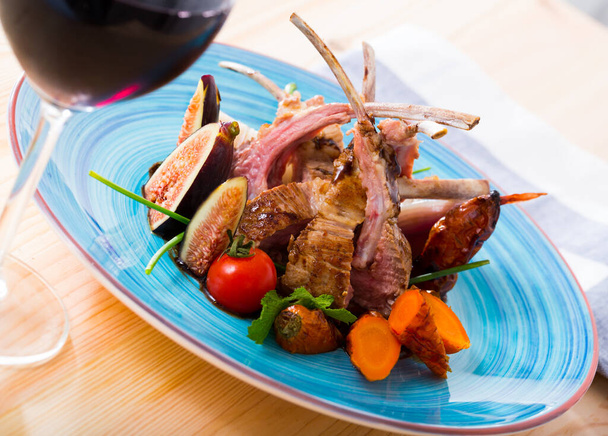Plate of roasted mutton ribs served with grilled vegetables and fresh figs - Foto, afbeelding