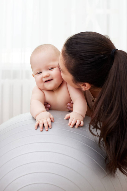 happy mother playing with her baby girl on a fitness ball at home - Foto, Imagem