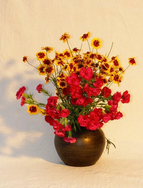 Boeket zomerbloemen in een kleivaas op een lichte stofondergrond. Perziken die in een diepe plaat naast elkaar staan - Foto, afbeelding