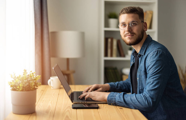 Portrait of bearded man freelancer working on laptop from home, coding remotely work - Valokuva, kuva