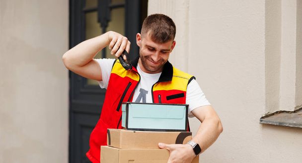 The happy courier scanning boxes a barcode packages with a handheld barcode scanner. High quality photo - Foto, imagen