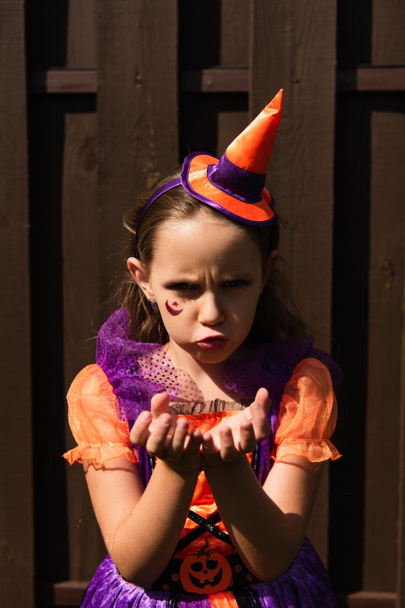 Mädchen im Halloween-Kostüm zeigt wütende Fratzen und gestikuliert, während sie in die Kamera schaut - Foto, Bild