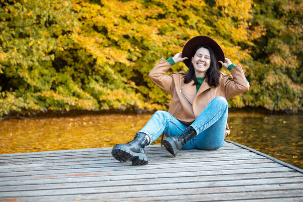 woman sitting on the pier view beautiful view of autumn lake with forest copy space - Foto, imagen