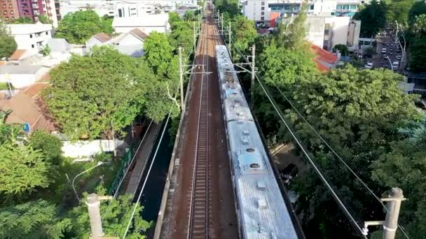 Vlaky osobní dopravy pohybující se po železnici ve městě a kamera z dronu se pohybuje jedním z městských vlaků. Zobrazení vlaku nahoře. - Záběry, video