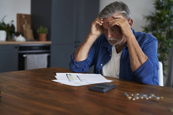 Senior man sitting at home with huge financial problems - Fotoğraf, Görsel