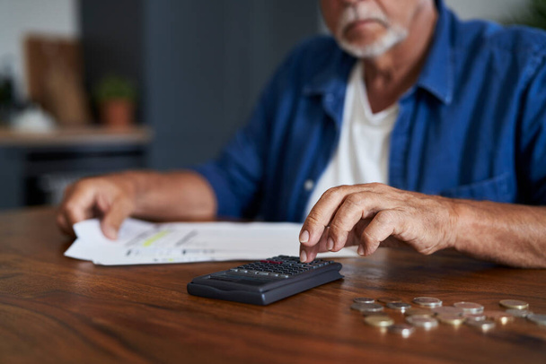 Uomo anziano che conta il budget di casa alla calcolatrice - Foto, immagini