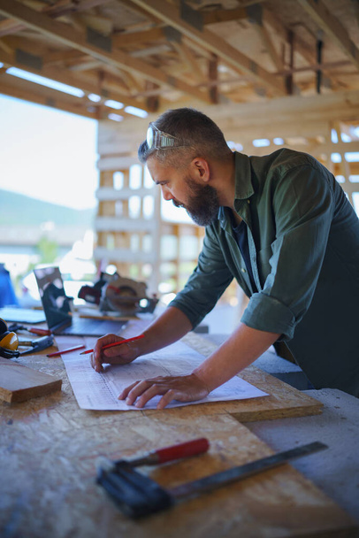 Construction worker smiling, drawing and checking a blueprints, diy eco-friendly homes concept. - Foto, imagen