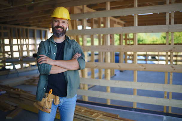 A portrait of construction worker smiling and looking at camera, diy eco-friendly homes concept. - Фото, изображение