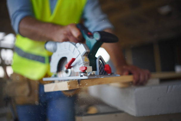 Close-up of construction worker working with eletric saw inside a wooden construction of house, diy eco-friendly homes concept. - Φωτογραφία, εικόνα