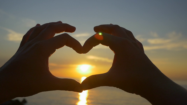 Przechwytywanie słońca z serca kształcie ręce - Materiał filmowy, wideo