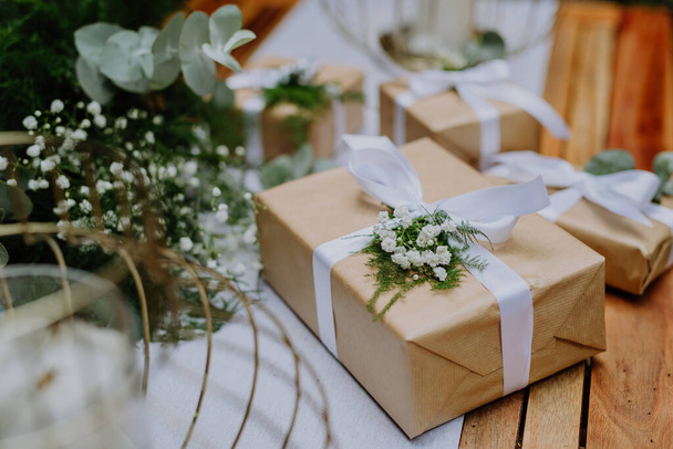 High angle view of wedding gift wrapped in eco paper papckaging and flower decoration. - Foto, afbeelding