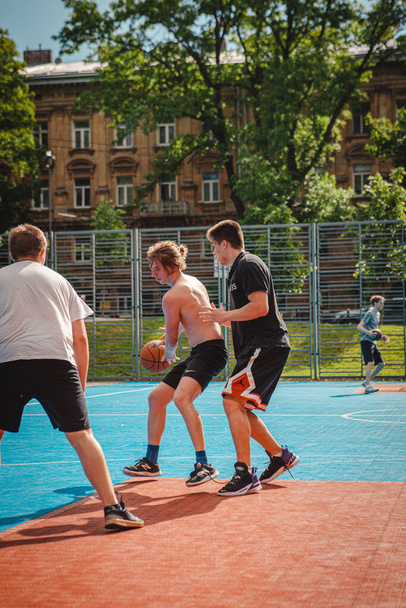 Львов, Украина - 28 мая 2022 года: мужчины играют в баскетбол на открытом воздухе в солнечный летний день - Фото, изображение