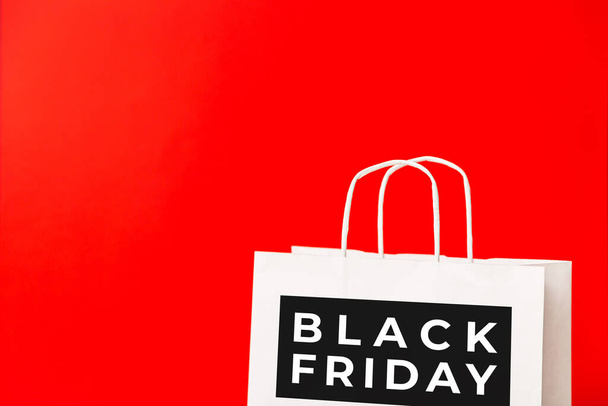 Black Friday weiße Papiertüte isoliert auf rotem Hintergrund. Black-Friday-Verkauf, Rabatt, Einkaufskonzept - Foto, Bild