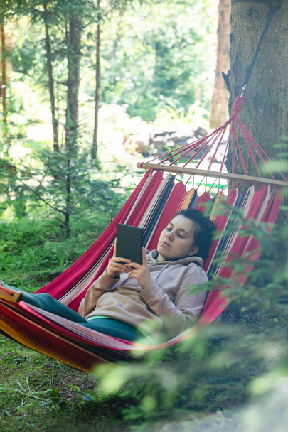 woman laying down in hammock reading book copy space - Photo, Image