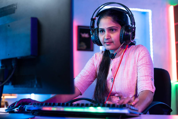 Mosolygós lány játszik online élő videojáték számítógépen beszél fejhallgatón otthon - koncepció a közösségi média megosztása, bajnokság és szerencsejáték-függőség. - Fotó, kép