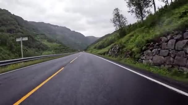First person view of a nordic two-lane road, forest, mountains - Felvétel, videó