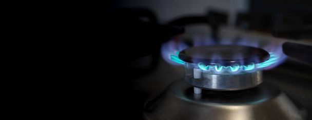 Banner de un primer plano de una llama de estufa de gas metano en una cocina doméstica con fondo negro para insertar su texto, relacionado con la crisis energética del precio del gas en Europa por un costo caro. - Foto, imagen