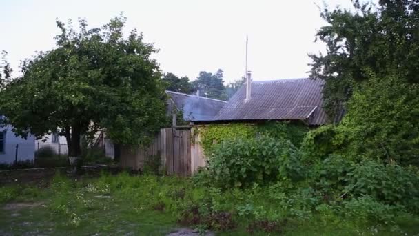 White smoke is discharged from a chimney on the tiled roof of a suburban home. Fume going up from the yard behind fence. Old village houses stand in a garden among trees and greenery - Footage, Video