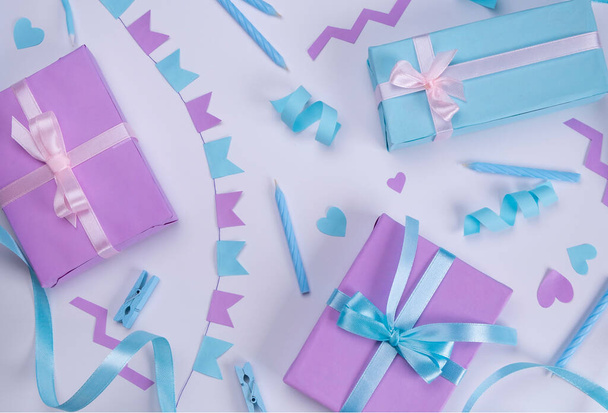 witte achtergrond met kaarsen, geschenkdozen, serpentijn en vakantie decoraties in blauwe en lila kleuren voor verjaardag of feest, verjaardag, jubileum, felicitaties concept.  - Foto, afbeelding