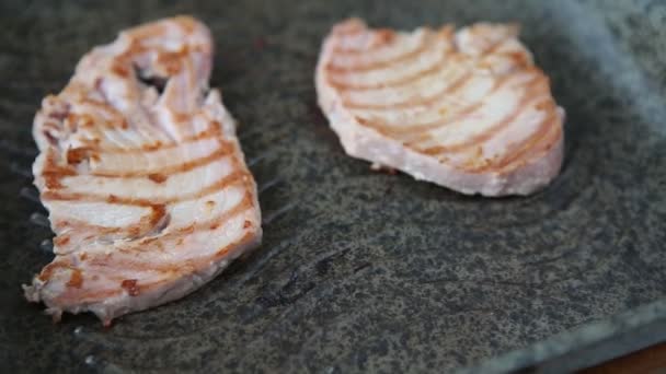 Kaksi viipaletta tonnikalan pihvejä paistetaan grillattu pannulla kuumalla höyryllä. Paistetun fileekalan keittäminen kuumalla pannulla öljyä lisäämättä - ruokavalio välimerellinen ruoka - Materiaali, video