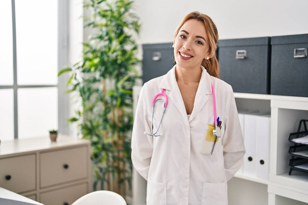 Mladá žena lékař usmívá sebevědomě stojí na klinice - Fotografie, Obrázek