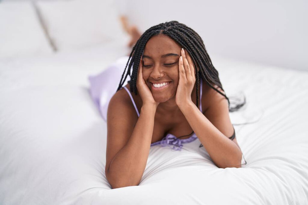 African american woman smiling confident lying on bed at bedroom - Foto, afbeelding