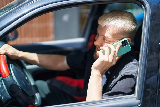 Nuori valkoihoinen mies puhuu älypuhelimella istuu autolla kadulla - Valokuva, kuva