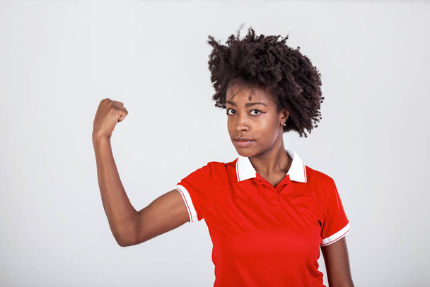 Photo of gorgeous strong young black woman isolated over white background showing biceps.Portrait of healthy young african woman flexing arm muscles on white background - Photo, Image