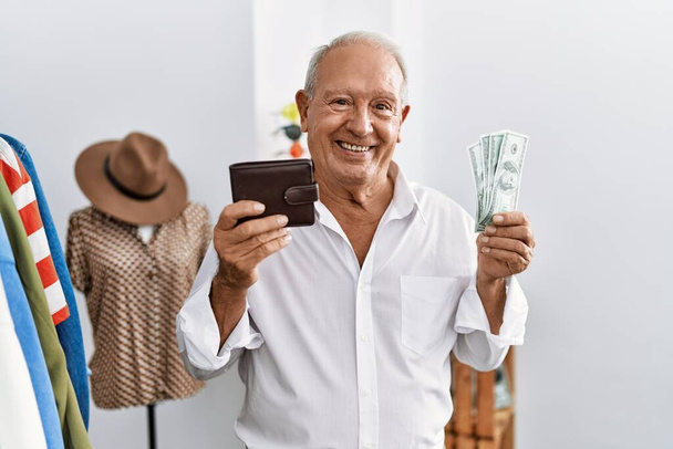 Senior man customer holding dollars and wallet at clothing store - 写真・画像