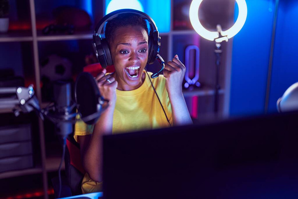 Afričanky americká žena streamer hrát videohru s vítězným výrazem v herně - Fotografie, Obrázek