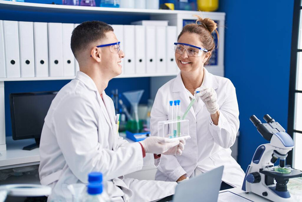 Man and woman scientists holding test tubes at laboratory - Φωτογραφία, εικόνα
