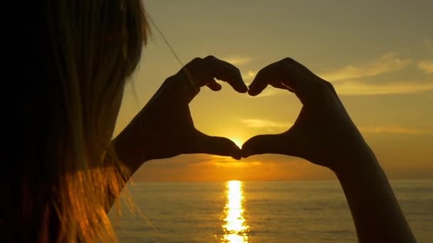Puesta de sol brillando a través de las manos en forma de corazón
 - Metraje, vídeo