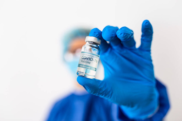 Opracowanie i stworzenie szczepionki koronawirusowej COVID-19. Koncepcja szczepionki koronawirusowej w ręku słoika zawierającego niebieską szczepionkę. Koncepcja szczepionki przeciwko koronawirusowi. - Zdjęcie, obraz