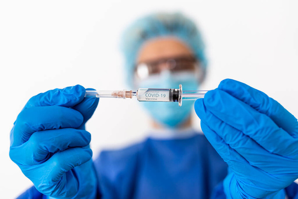 Epidemie des chinesischen Coronavirus. Ärztin in Schutzanzug und Maske hält Spritze und Impfstoff in der Hand. Impfung gegen Grippe, Coronavirus - Foto, Bild