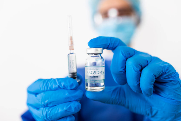 Doctor, nurse, scientist, researcher hand in blue gloves holding flu, measles, coronavirus, covid-19 vaccine disease preparing for human clinical trials vaccination shot, medicine and drug concept. - Photo, image