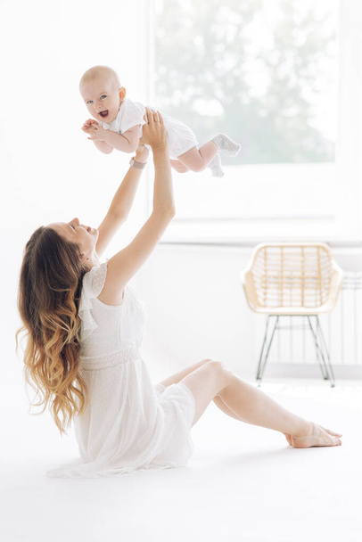 Giovane madre felice si siede e gioca con il suo bambino su sfondo bianco. Primo piano. - Foto, immagini