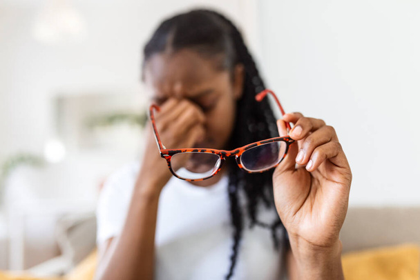 African girl in glasses rubs her eyes, suffering from tired eyes, ocular diseases concept - Foto, Imagen