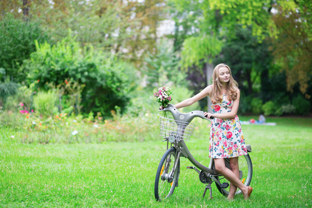 Gelukkig jong meisje met fiets en bloemen - Foto, afbeelding