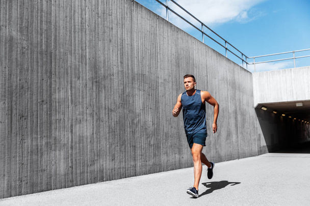 fitness, sport and healthy lifestyle concept - young man running out of tunnel - Foto, afbeelding