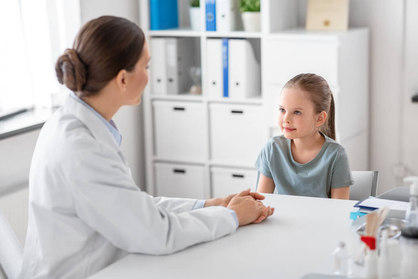 medicine, healthcare and pediatry concept - female doctor or pediatrician talking to little girl patient on medical exam at clinic - Foto, Imagen