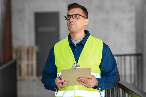 architecture, construction business and building concept - male architect in safety west with clipboard working at office - Φωτογραφία, εικόνα