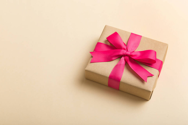 Verhüllte Weihnachten oder andere Feiertage handgemachtes Geschenk in Bastelpapier mit farbigem Band. Geschenkschachtel, Geschenkdekoration auf dem Tisch, Draufsicht mit Kopierraum. - Foto, Bild