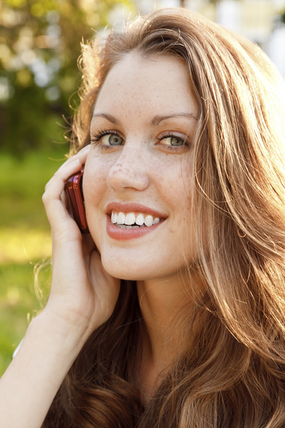携帯電話で話す若い女性の屋外のポートレート - 写真・画像