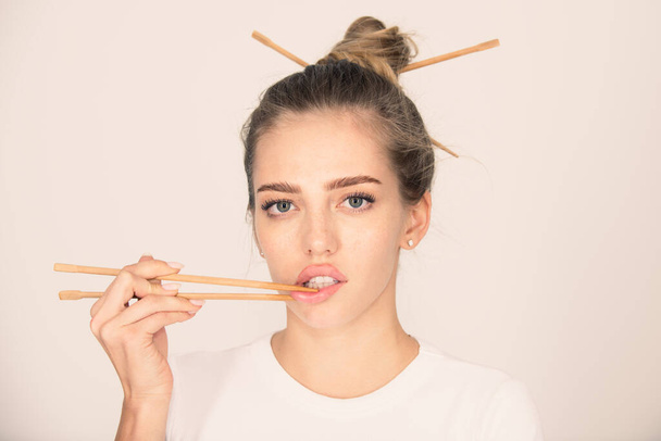 Chopsticks near sexy lips mouth. Sexy woman touch sensual lips with chopsticks. Sushi advertising - Foto, afbeelding