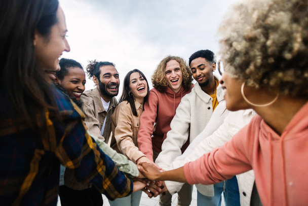 Heureux jeune groupe de personnes multiraciales empilant les mains à l'extérieur - concept de communauté et d'unité - Photo, image