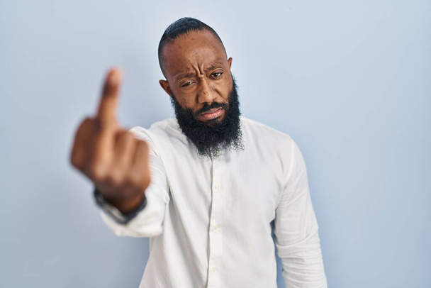 African american man standing over blue background showing middle finger, impolite and rude fuck off expression  - Foto, Bild